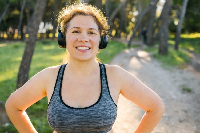 Woman and sports. Girl doing exercise for weight loss in the fresh air and laughing in camera after training.