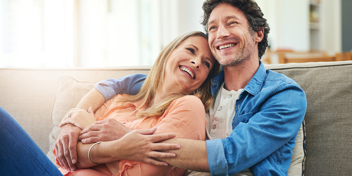 a happy couple sitting on couch embracing each other