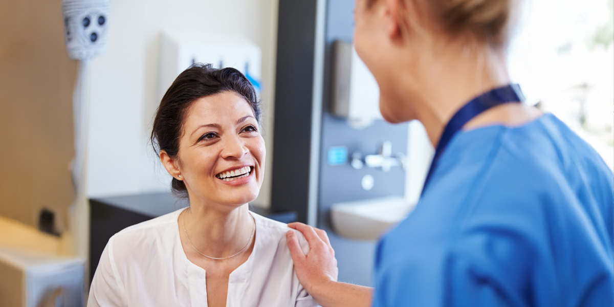 a smiling female patient meets with her doctor