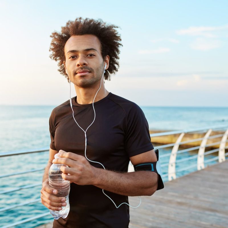 dark-skinned-cheerful-sportsman-drinking-water